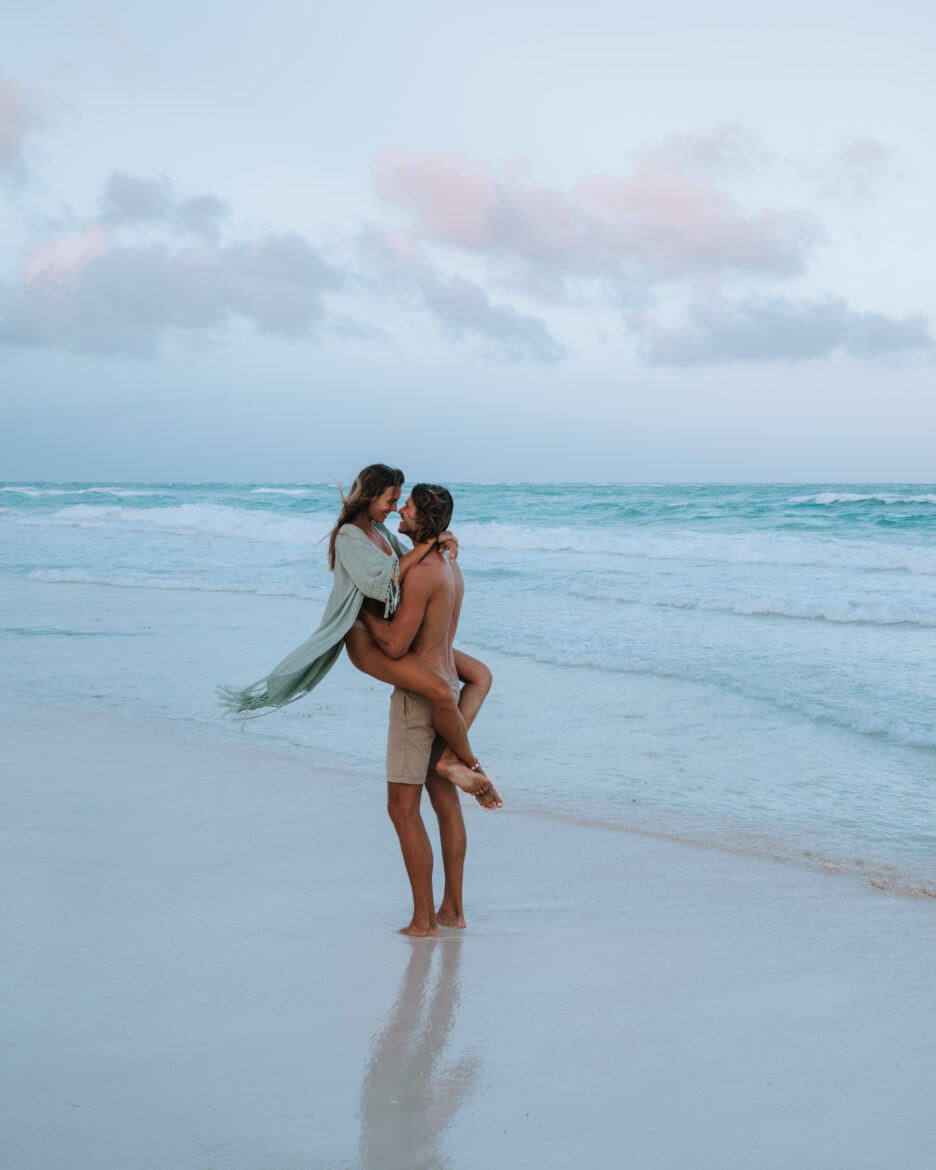 A couple hugging on the beach at sunset.