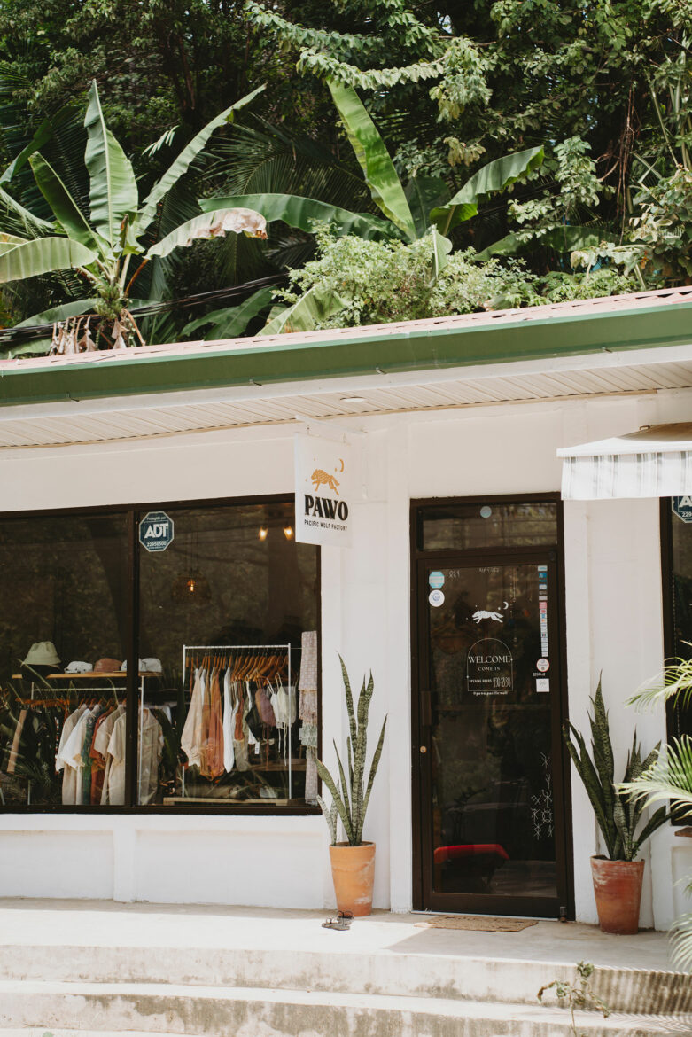 A store front with plants and a sign.