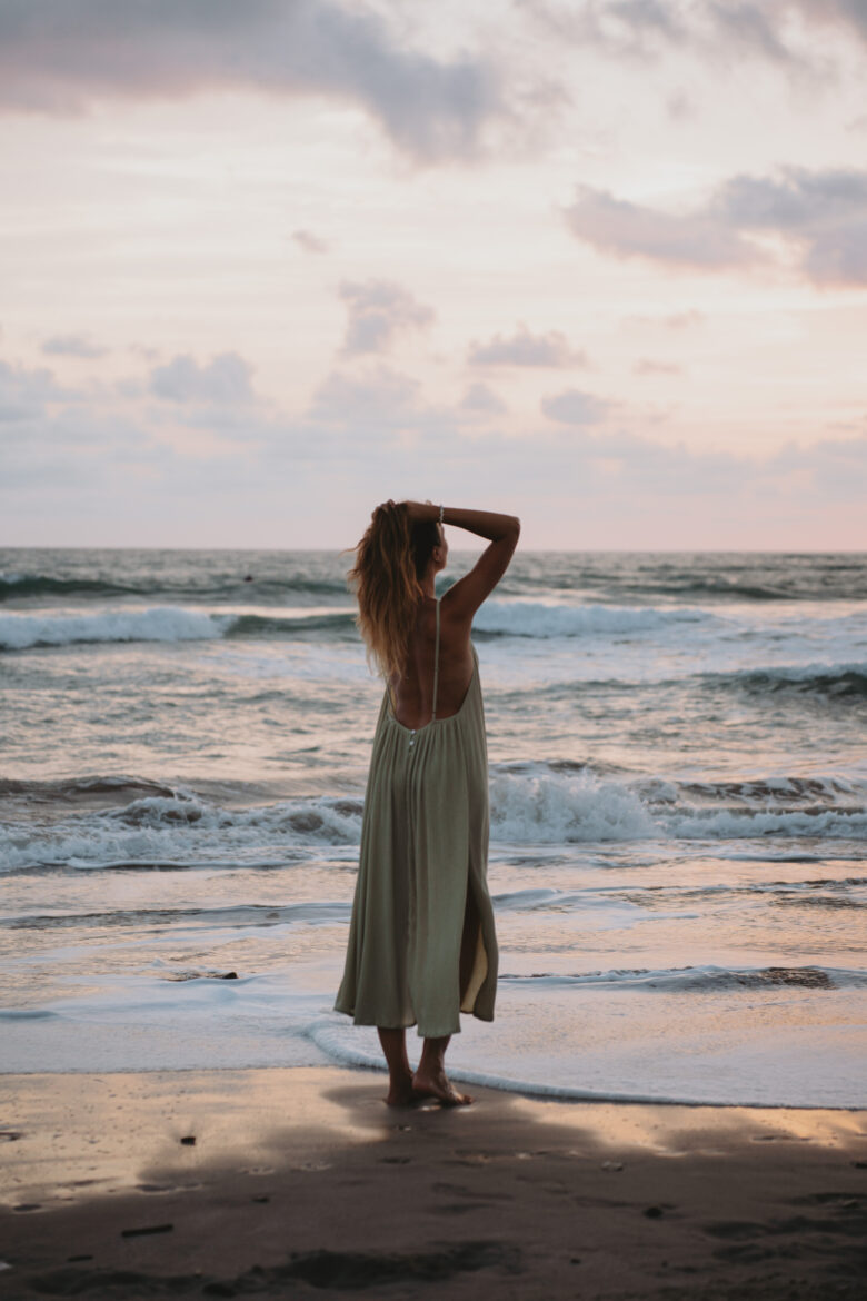 A woman standing on the beach in Santa Teresa, Costa Rica at sunset.