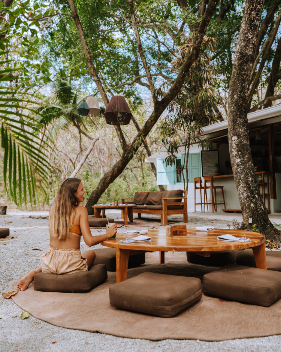 A woman sitting at a table under a tree.